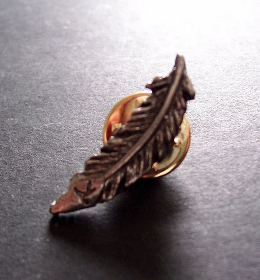 Before the Dawn feather pin badge incorporating tiny KT symbol – designed by Jordan Atkinson